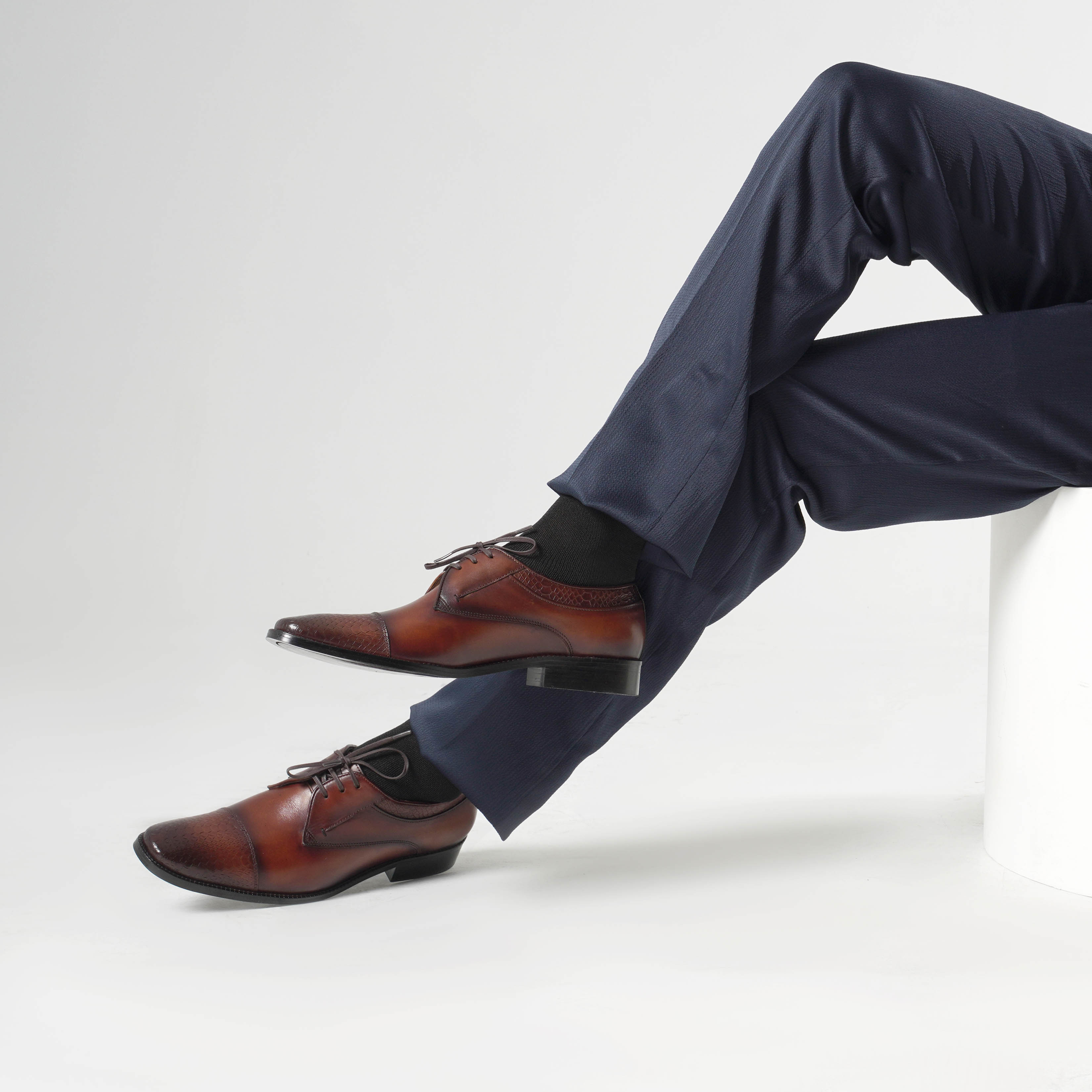 Brown dress shoes and navy pants on a white background